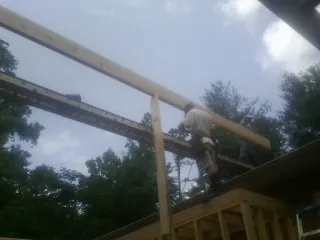 Carpenter setting a ridge beam over a new addition frame — Ice Dam Removal by Roofing Brothers in Hiawatha