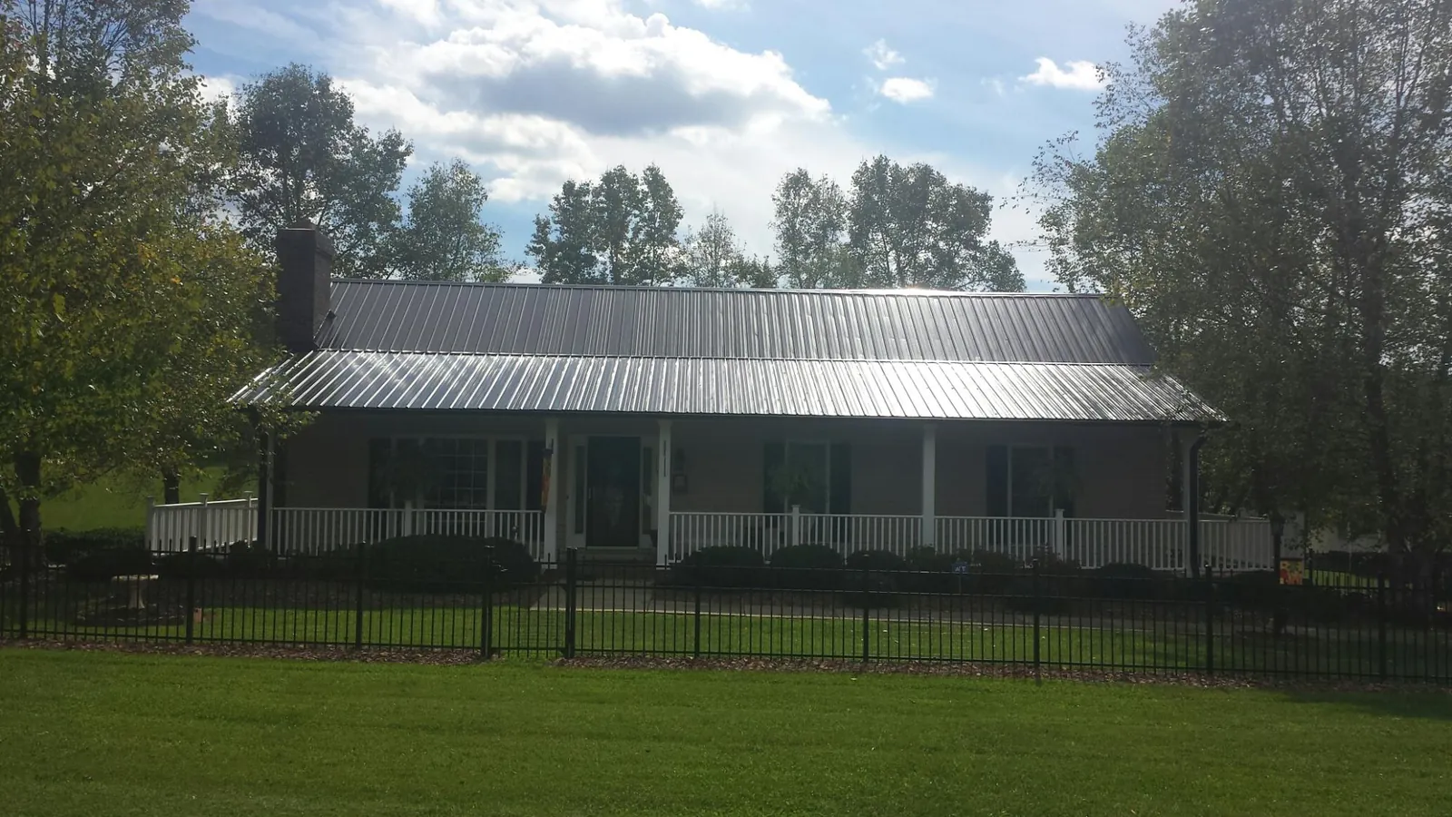 Gray metal roof on a brick ranch with a full width front porch — Gutter Guard Installation work by our crew in Hiawatha