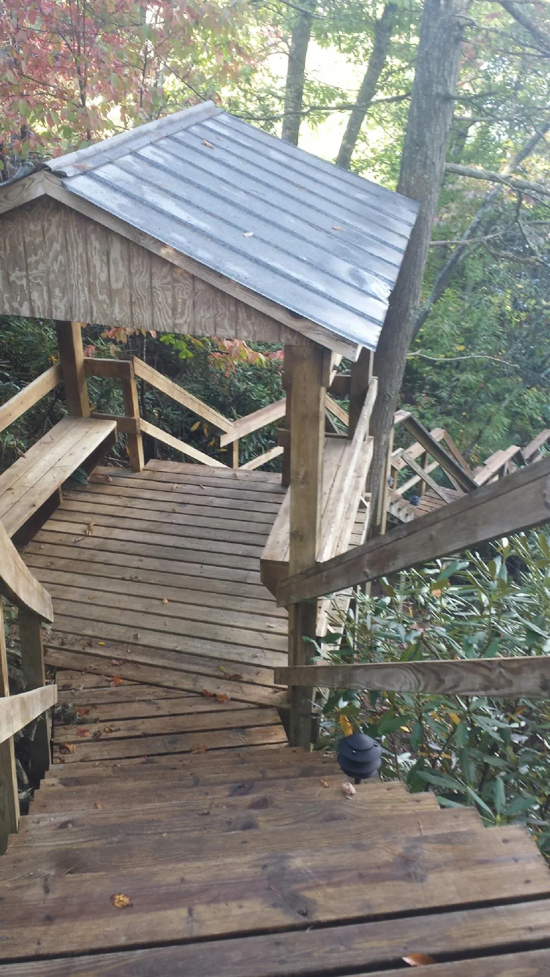 Metal roofed shelter over wooden steps on a wooded walkway — Skylight Repair & Installation work by our crew in Hiawatha