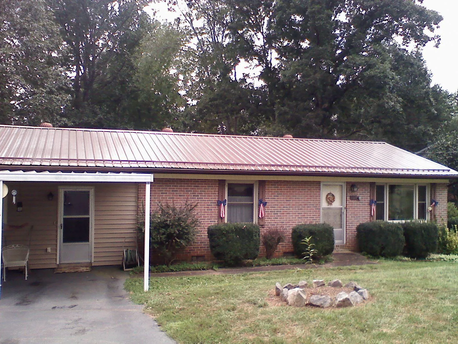 Bronze metal roof and carport on a brick ranch home — Roof Repair work by our crew in Hiawatha